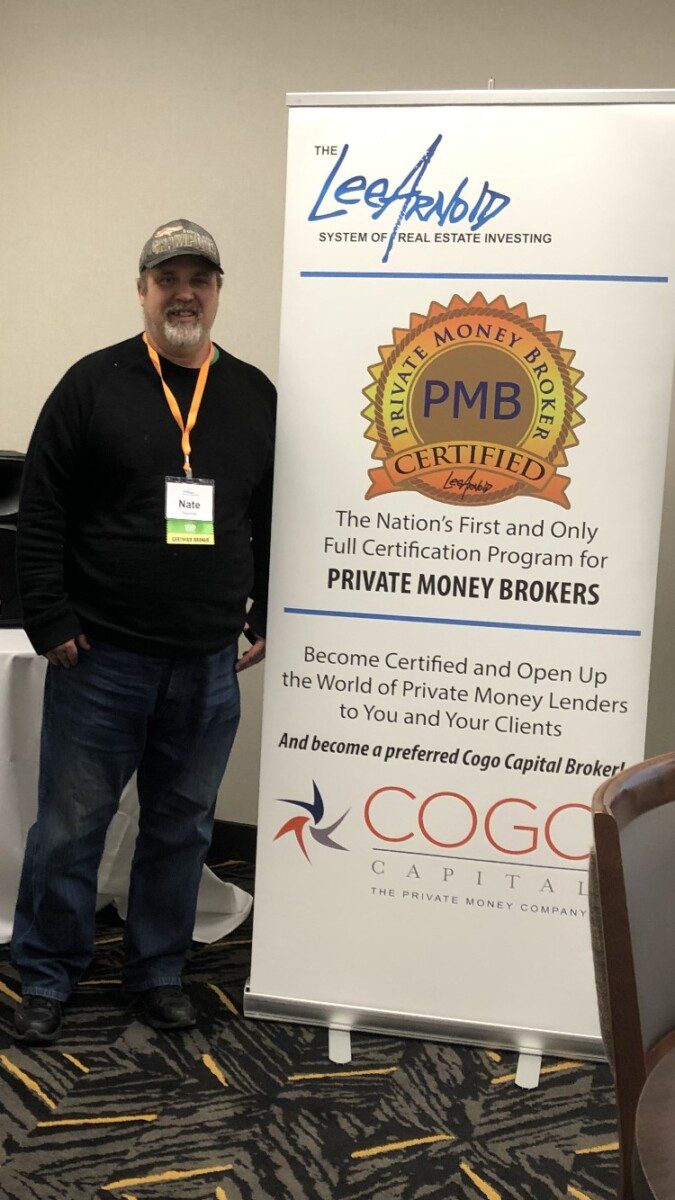 A man is standing next to a promotional banner at a professional event or seminar.